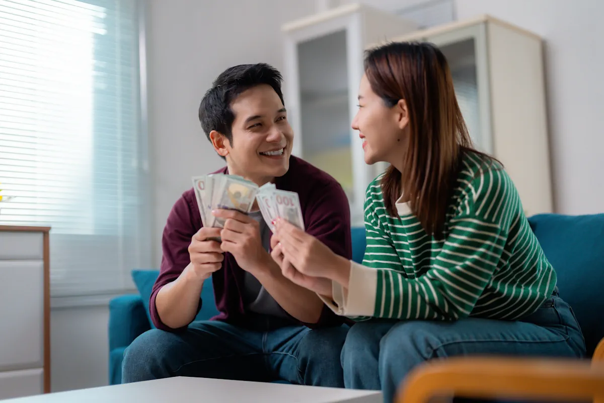 Un couple qui compte l'argent du remboursement de leur thérapie de couple sur un canapé